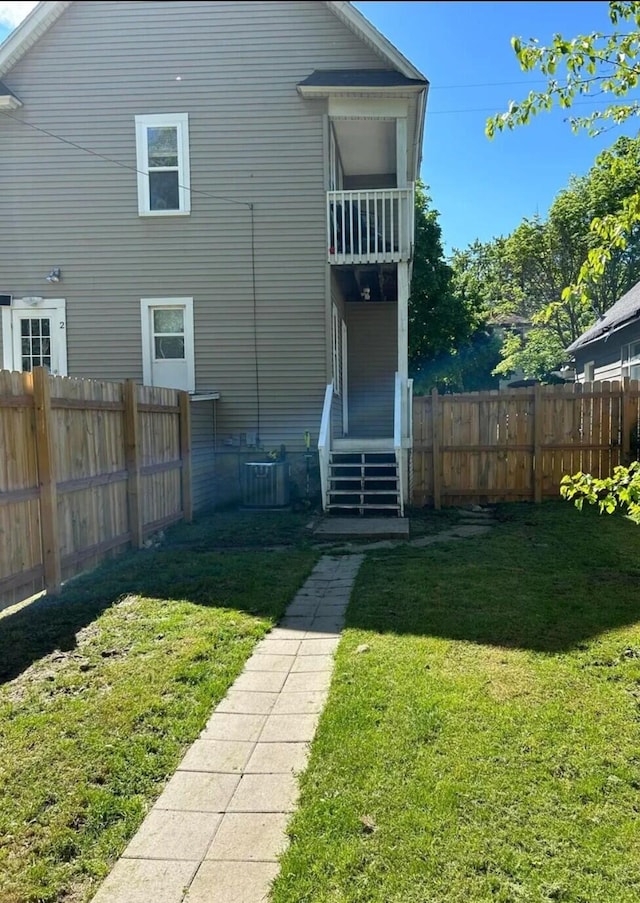 rear view of property featuring central AC unit and a yard