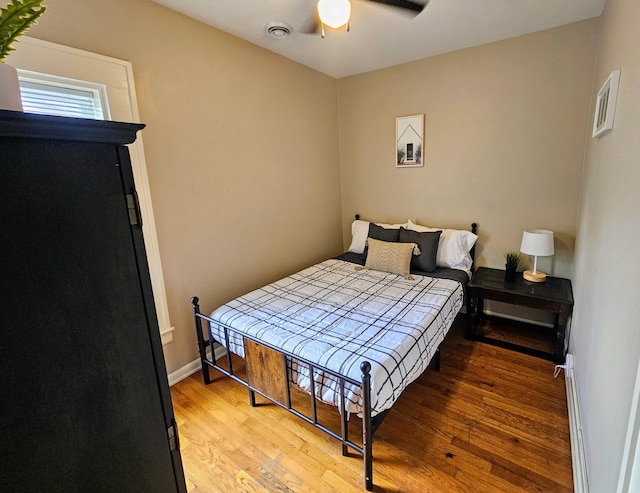 bedroom with hardwood / wood-style floors, ceiling fan, and a baseboard radiator