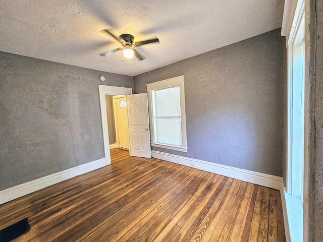 unfurnished bedroom with a textured ceiling, ceiling fan, and dark wood-type flooring