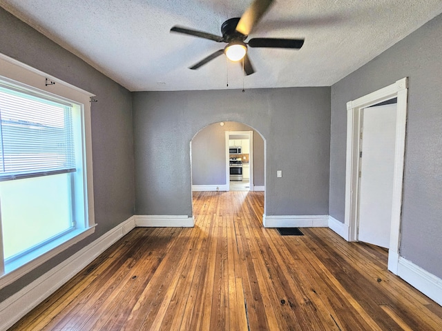 unfurnished room featuring dark hardwood / wood-style floors, ceiling fan, and a textured ceiling