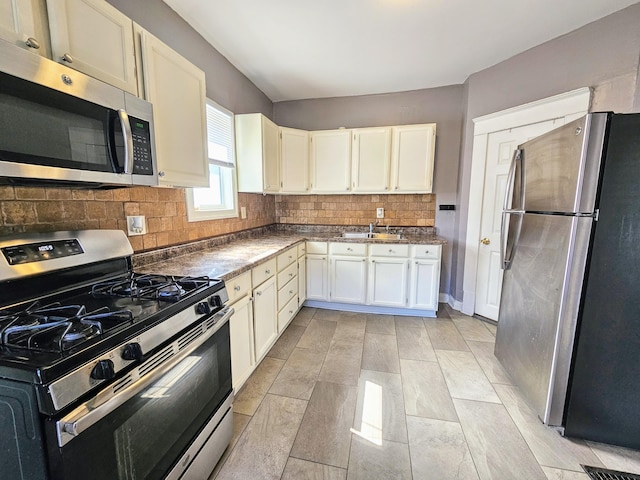 kitchen with white cabinets, sink, appliances with stainless steel finishes, and tasteful backsplash