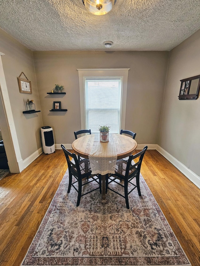 dining area featuring wood-type flooring and a textured ceiling