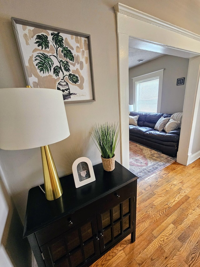 hall featuring light wood-type flooring and a textured ceiling