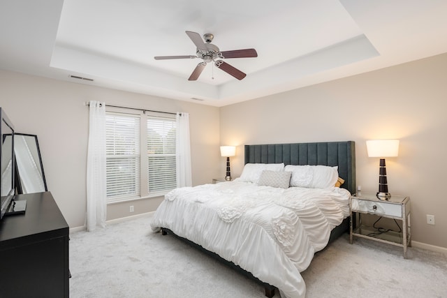 carpeted bedroom featuring a raised ceiling and ceiling fan