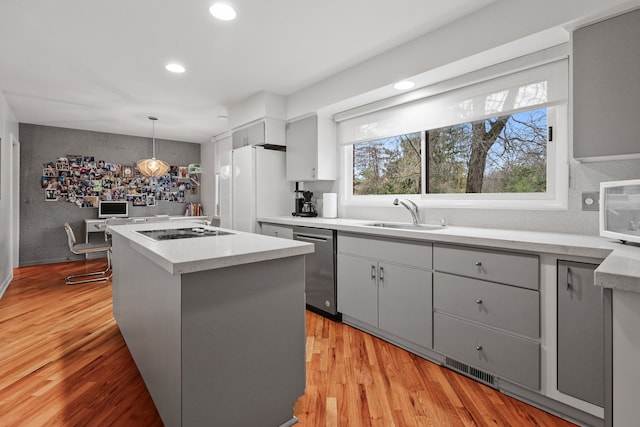 kitchen featuring dishwasher, white refrigerator, sink, light hardwood / wood-style flooring, and decorative light fixtures