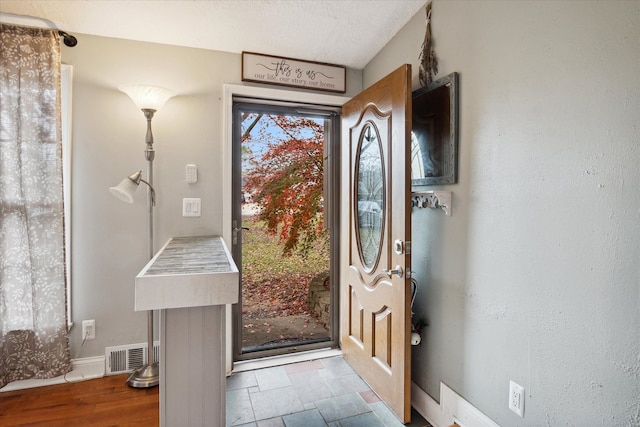 entryway with a textured ceiling and hardwood / wood-style flooring