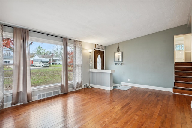 interior space featuring a textured ceiling, a wealth of natural light, hardwood / wood-style floors, and lofted ceiling