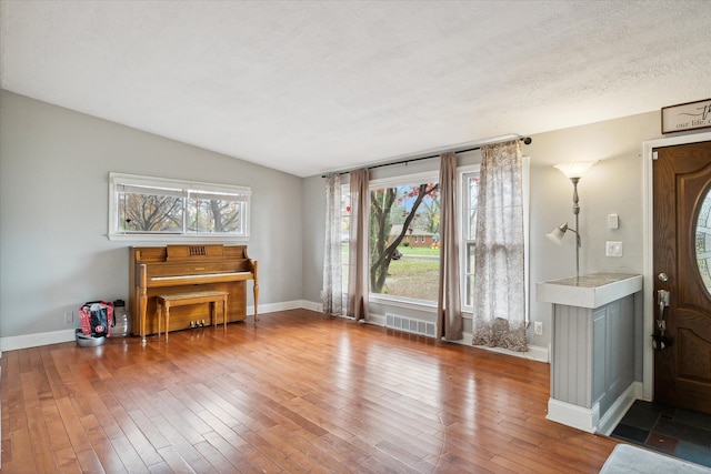 entrance foyer featuring hardwood / wood-style floors, lofted ceiling, and a textured ceiling