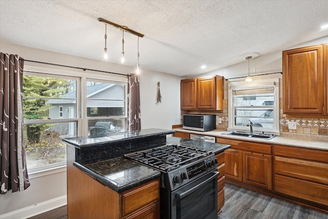 kitchen featuring sink, hanging light fixtures, tasteful backsplash, vaulted ceiling, and appliances with stainless steel finishes