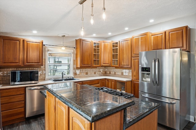 kitchen with decorative backsplash, appliances with stainless steel finishes, sink, pendant lighting, and a kitchen island