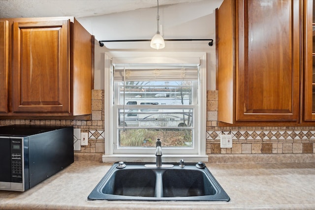 kitchen with pendant lighting, decorative backsplash, lofted ceiling, and sink