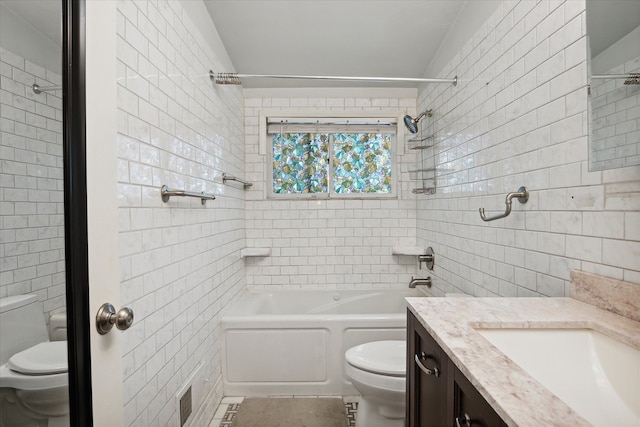 full bathroom featuring tile patterned flooring, toilet, vanity, tile walls, and tiled shower / bath