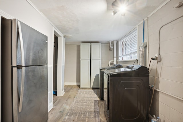 washroom featuring washer and clothes dryer, light hardwood / wood-style flooring, and ornamental molding