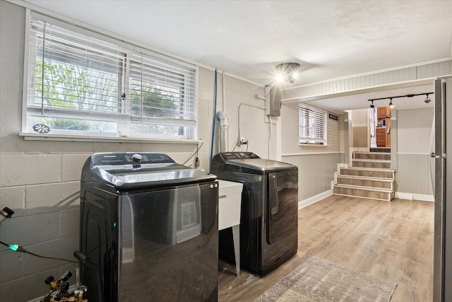 washroom with washing machine and clothes dryer and light hardwood / wood-style flooring