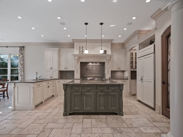 kitchen with decorative light fixtures, ornamental molding, a kitchen island with sink, and tasteful backsplash