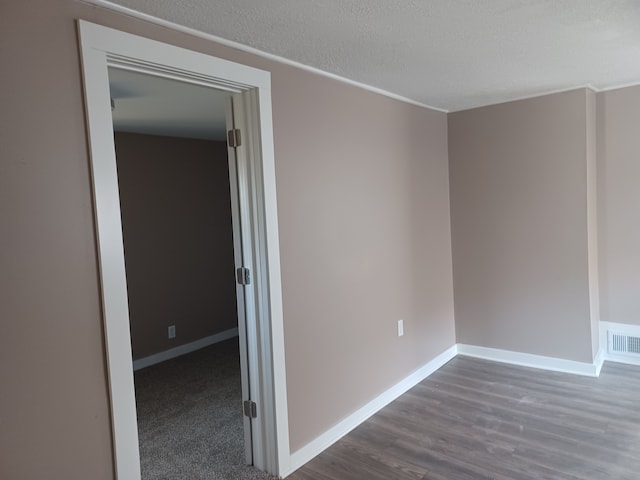 unfurnished room featuring dark wood-type flooring and a textured ceiling