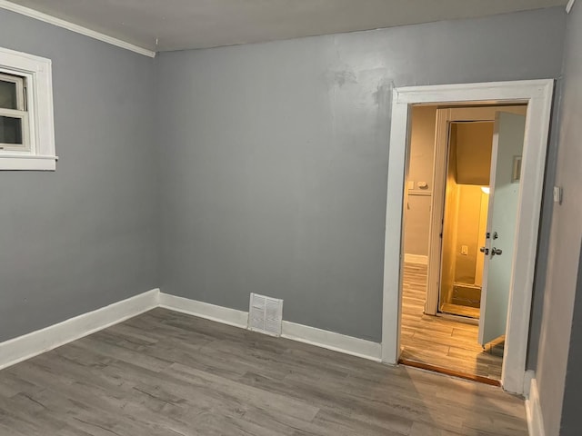 unfurnished room with hardwood / wood-style flooring and crown molding