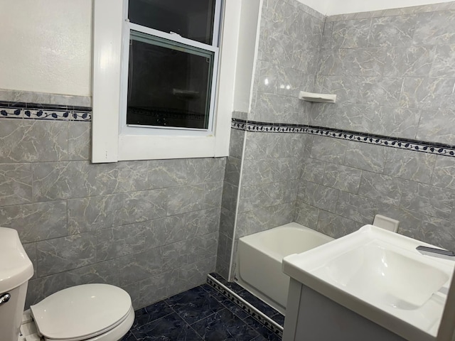 bathroom featuring vanity, toilet, and tile walls