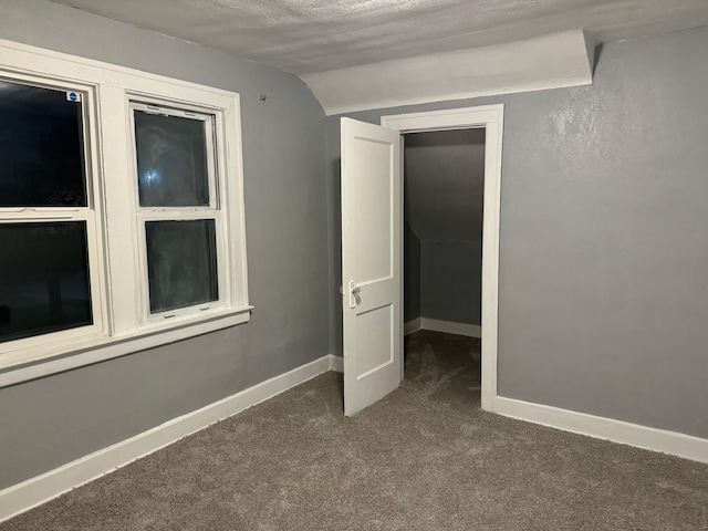 carpeted spare room featuring a textured ceiling and lofted ceiling