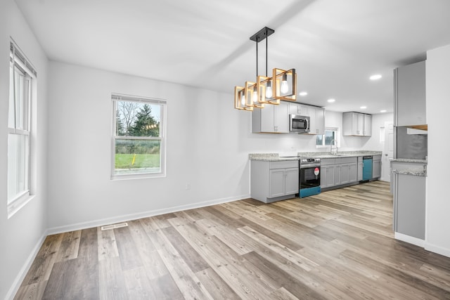 kitchen with sink, gray cabinets, decorative light fixtures, light hardwood / wood-style floors, and stainless steel appliances