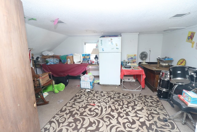 interior space with white fridge, lofted ceiling, and a textured ceiling