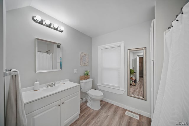 bathroom featuring hardwood / wood-style floors, vanity, toilet, and lofted ceiling