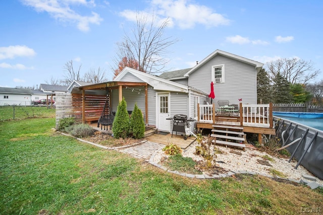 back of property with a swimming pool side deck and a lawn