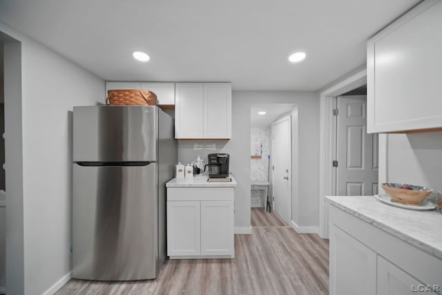 kitchen with stainless steel fridge, light hardwood / wood-style flooring, white cabinets, and light stone countertops