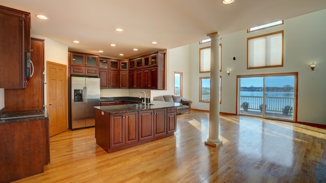 kitchen with a kitchen island with sink, a water view, light hardwood / wood-style floors, and appliances with stainless steel finishes