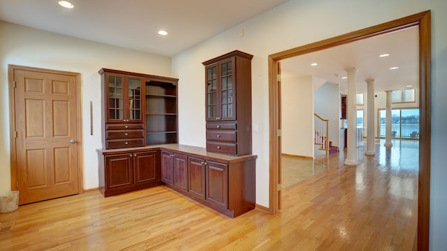 bar with light wood-type flooring and decorative columns