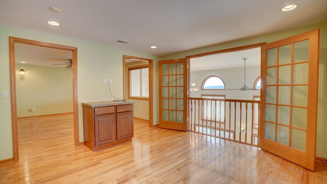 unfurnished room with french doors, light wood-type flooring, and ceiling fan