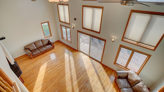 entryway featuring ceiling fan with notable chandelier, a high ceiling, and light wood-type flooring