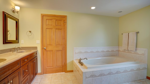 bathroom featuring tile patterned flooring, vanity, and tiled tub