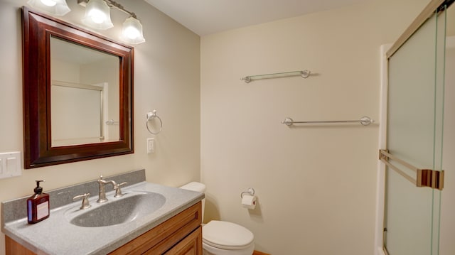 bathroom featuring vanity, toilet, and a shower with shower door