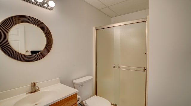 bathroom featuring a drop ceiling, toilet, walk in shower, and vanity