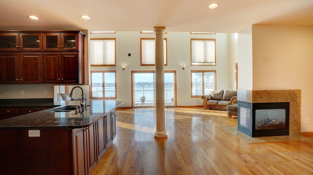 kitchen with plenty of natural light, decorative columns, sink, and light hardwood / wood-style flooring