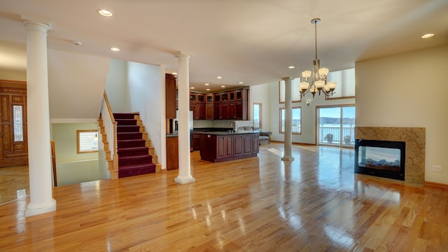 unfurnished living room with a multi sided fireplace, light hardwood / wood-style flooring, a chandelier, and sink