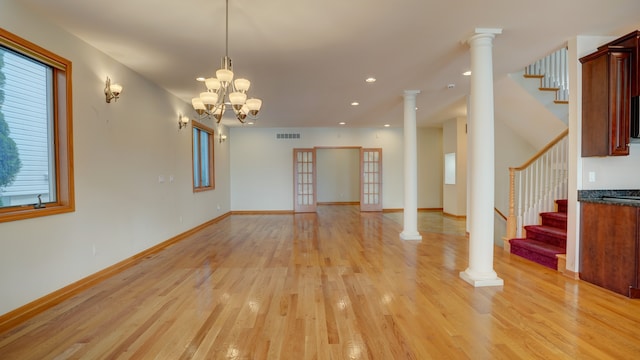 unfurnished living room with a notable chandelier, light wood-type flooring, and french doors