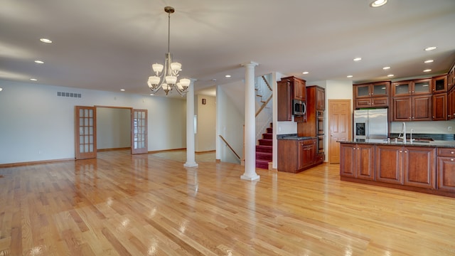 kitchen with a chandelier, appliances with stainless steel finishes, light wood-type flooring, and hanging light fixtures