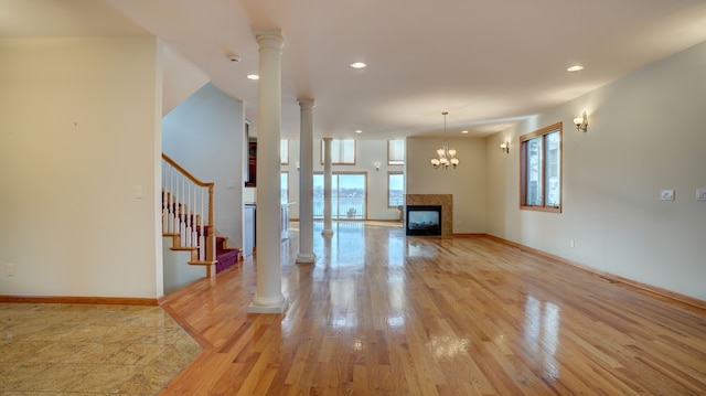 unfurnished living room featuring a multi sided fireplace, light hardwood / wood-style flooring, and a notable chandelier