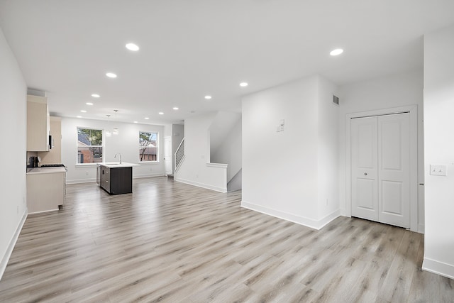 unfurnished living room with light wood-type flooring and sink