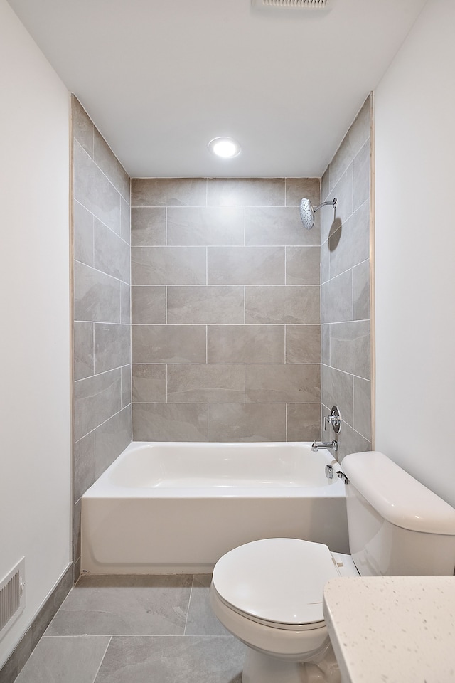 bathroom with tile patterned flooring, toilet, and tiled shower / bath