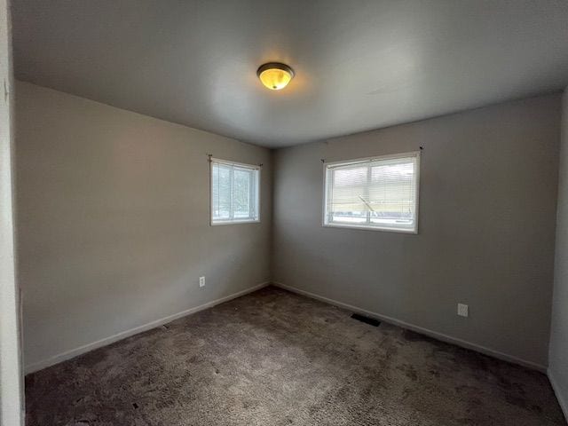 unfurnished room with dark colored carpet