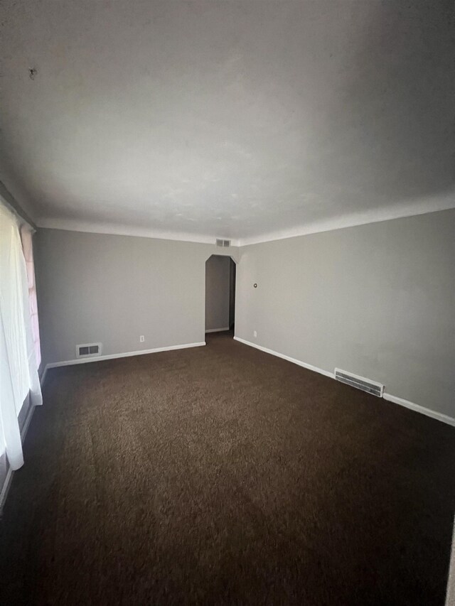 2910 Shawnee Ave, Flint, MI 48507 - unfurnished room featuring arched walkways, baseboards, and dark colored carpet