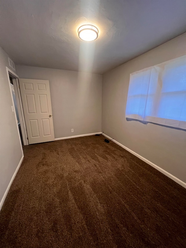 unfurnished room featuring dark colored carpet