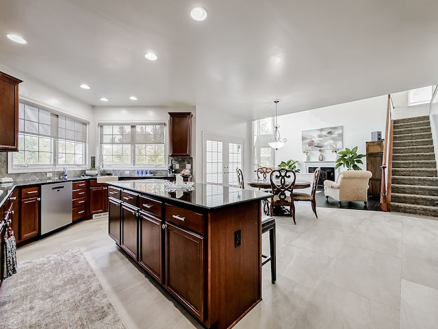 kitchen with a center island, hanging light fixtures, tasteful backsplash, stainless steel dishwasher, and a kitchen bar