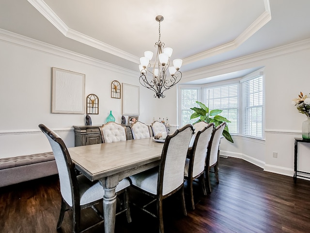 dining area with a tray ceiling, ornamental molding, dark hardwood / wood-style floors, and an inviting chandelier