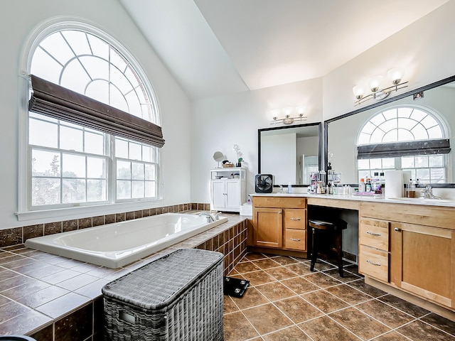 bathroom featuring tile patterned flooring, lofted ceiling, a relaxing tiled tub, and a healthy amount of sunlight