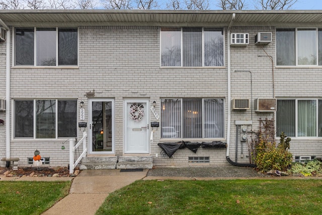 townhome / multi-family property featuring an AC wall unit and a front lawn