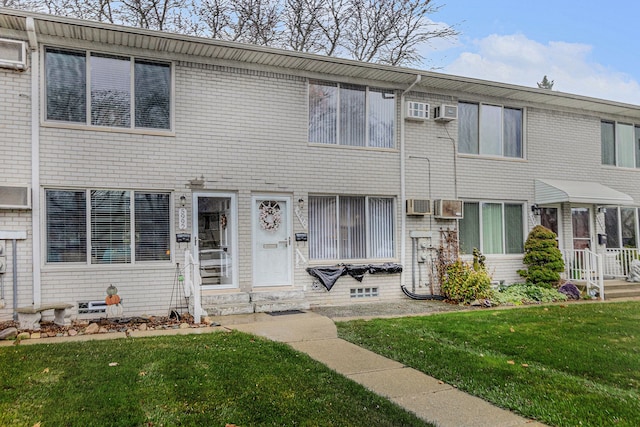 view of property featuring an AC wall unit and a front yard